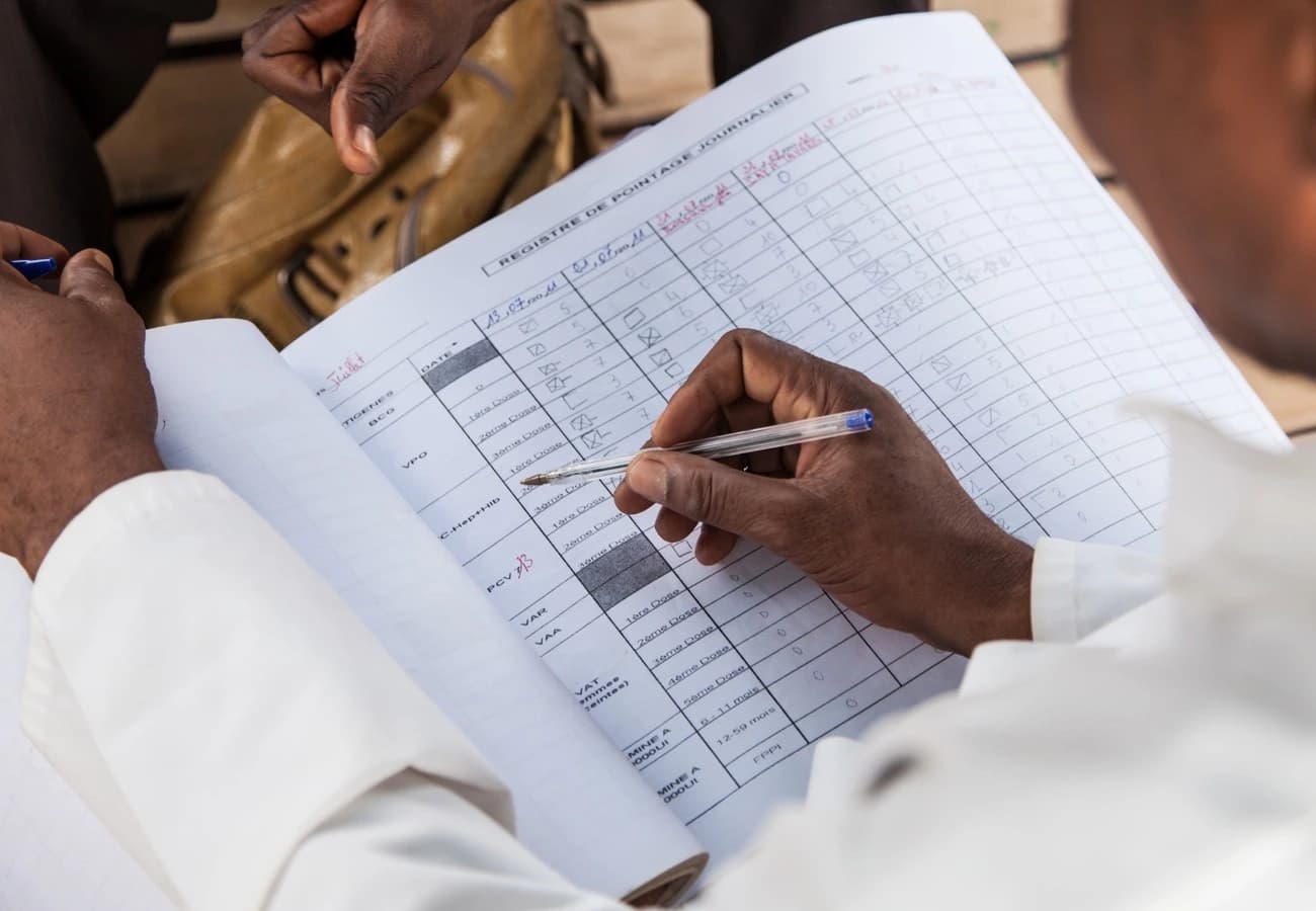 Das Bild zeigt ein Blatt, auf dem unsere Mitarbeitenden Gesundheitsdaten eintragen. Das Foto wurde aus der Sicht eines Mitarbeitenden aufgenommen, das Blatt liegt auf seinem Schoss. Man sieht seine Hand mit einem Kuglelschreiber, er trägt etwas darauf ein.