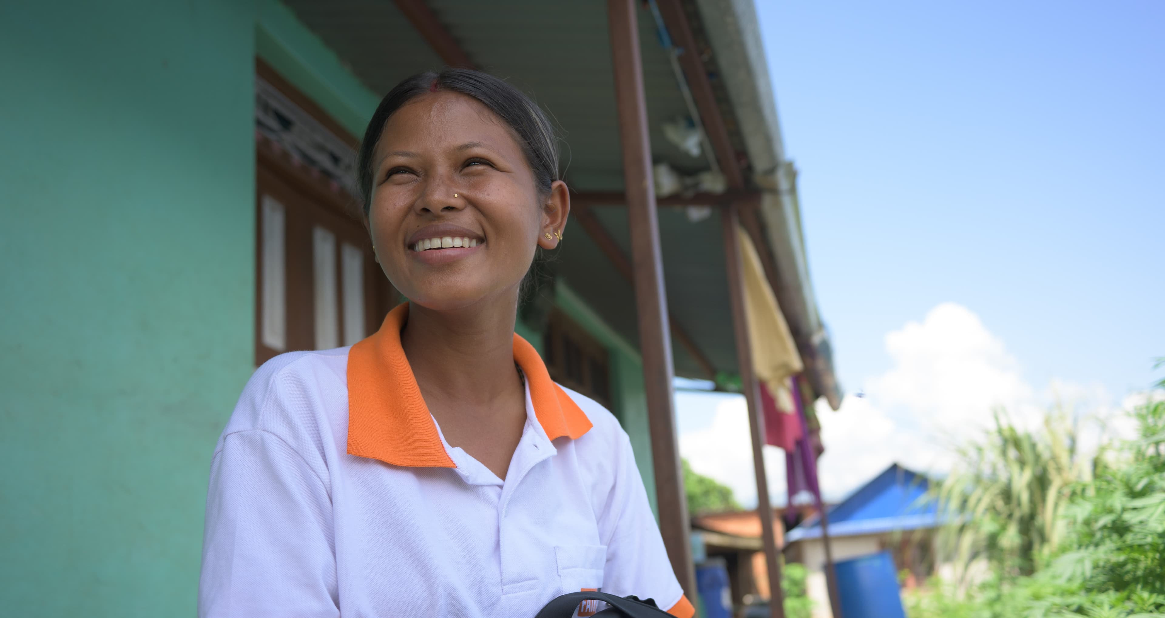 Sujita est assise devant une maison, le sourire aux lèvres.