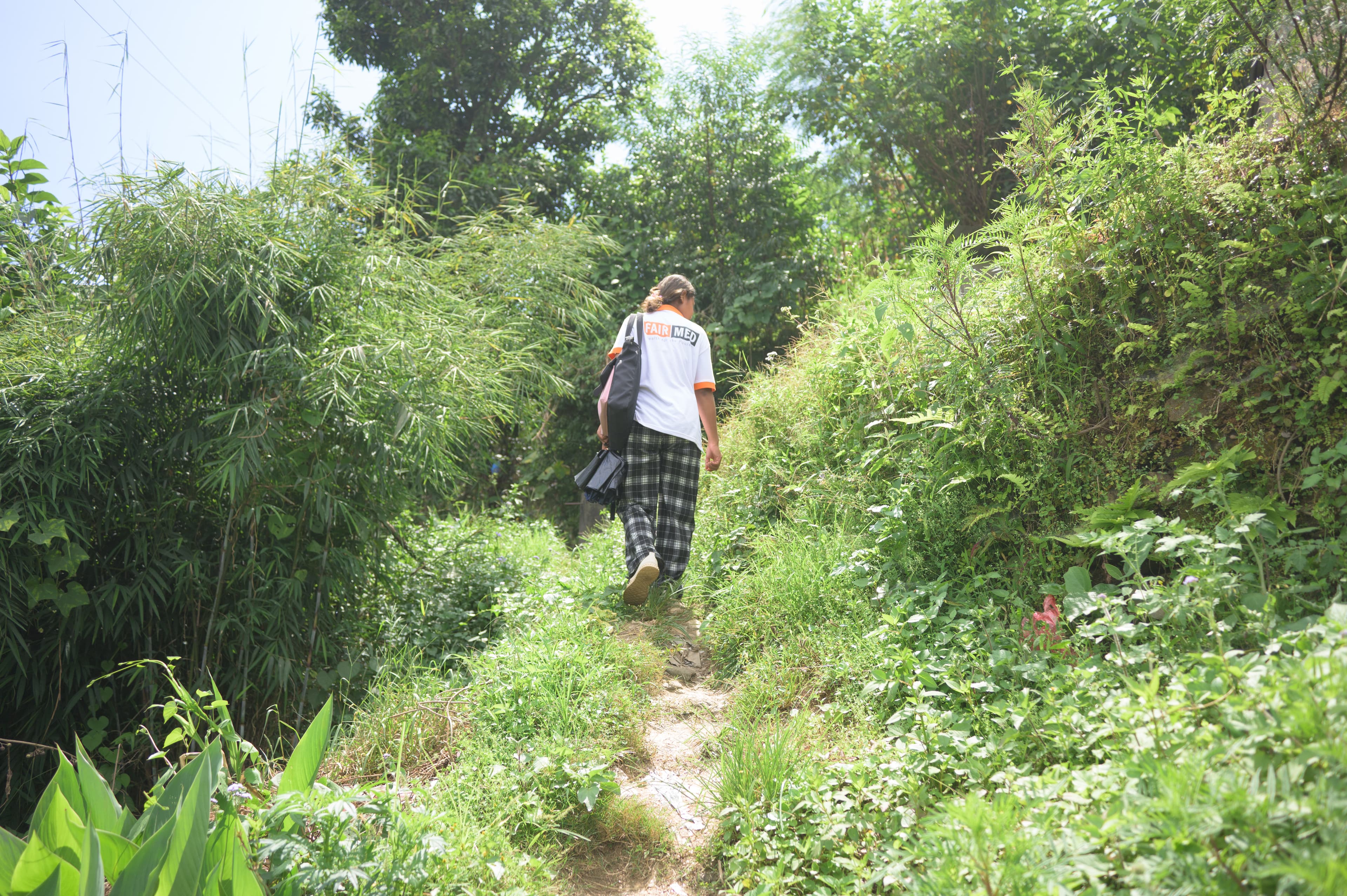 Sur la photo, on voit Sujita de dos, en train de monter un chemin escarpé. Le chemin est entouré de nombreuses plantes.
