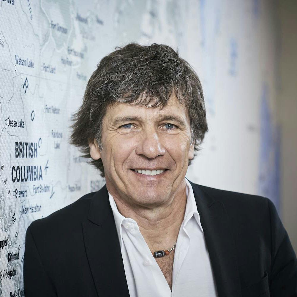 André Lüthi porte une chemise blanche et un blazer noir. Il se tient devant un mur blanc.