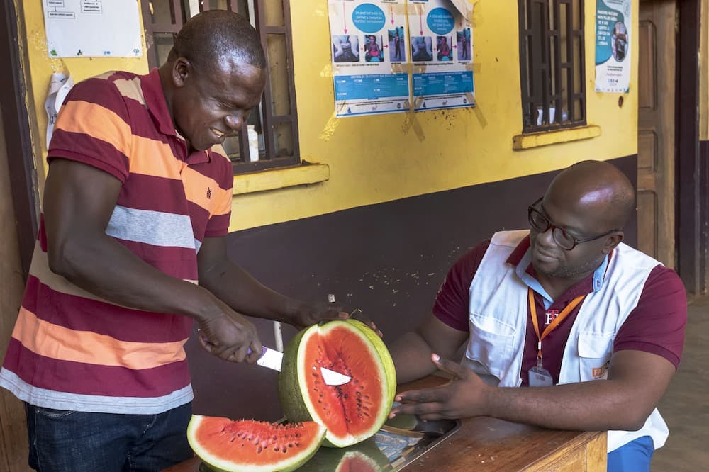 Deux collaborateurs de FAIRMED coupent les melons dont le produit sert à financer leur caisse maladie.